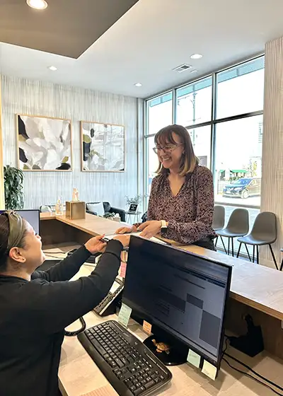 A woman being given a form by the receptionist at Chicago Oral Surgery and Implant Center.