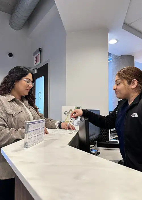 A receptionist helping her patient fill out insurance paperwork on a clipboard