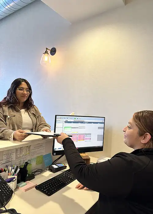 A patient talking to a receptionist about her appointment at Chicago Oral Surgery and Implant Center.