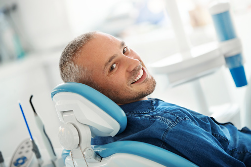 Man smiling in chair at Chicago Oral Surgery and Implant Center].