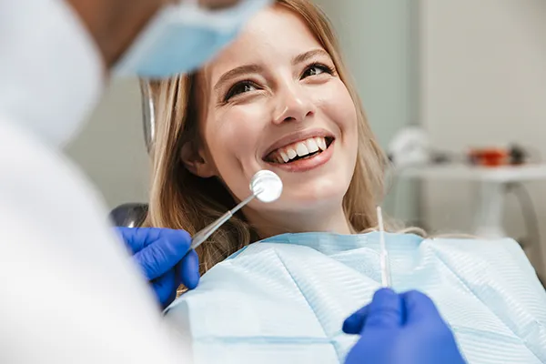 Female patient happily waiting in a dental chair for her dentist to begin her routine dental exam.