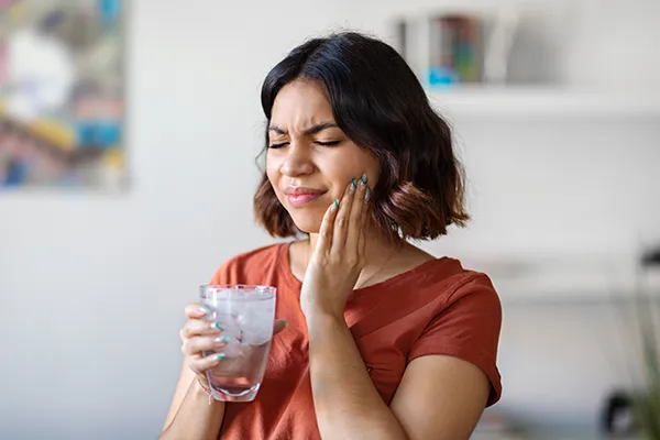 Young woman rubbing her jaw and wincing in pain